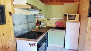 A compact kitchen with a stove, sink, and a microwave.
