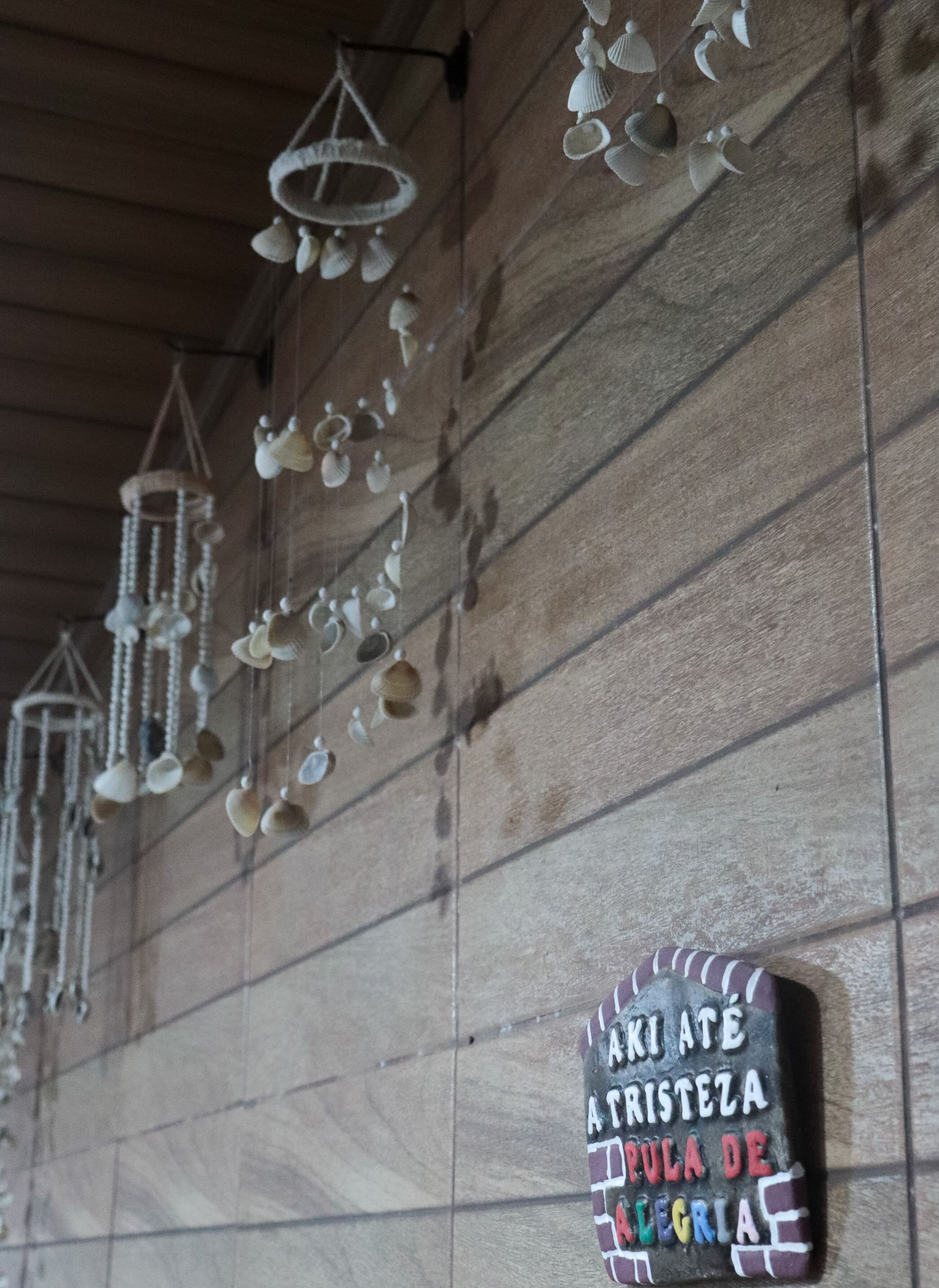 A wall with hanging decorative items and a sign with text.