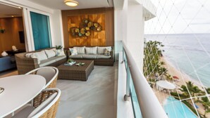 Un balcó amb vista a l'oceà, una zona de seients amb un sofà i cadires, i un ventilador de sostre.