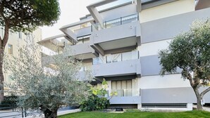 Ein modernes Mehrfamilienhaus mit Balkonen, einem gepflegten Rasen und ausgewachsenen Bäumen.