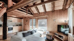 Interior moderno de una cabaña de troncos con sala de estar, cocina y comedor.