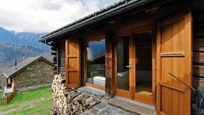 Una cabaña de madera con base de piedra, amplios ventanales y vistas a montañas.