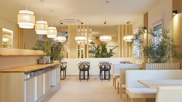 Un restaurant moderne avec un comptoir en bois, de nombreuses tables et des luminaires suspendus.