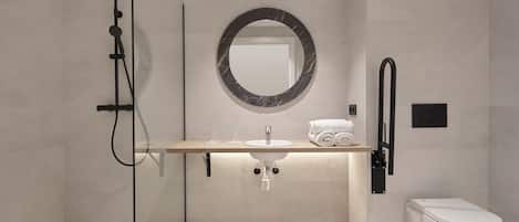 Une salle de bain moderne avec une douche à parois de verre, un miroir rond, un lavabo avec un plan de toilette en marbre et des toilettes.