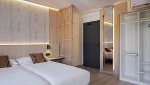 Une chambre d’hôtel moderne avec un grand lit, une armoire et un bureau avec une chaise.