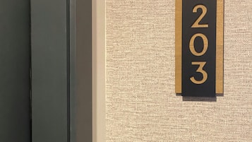 A textured wall with a black and gold number sign indicating room number 203.