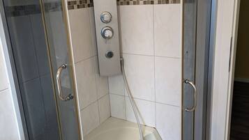 Chuveiro, toalhas de banho, sabonete, papel higiênico