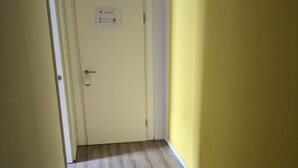 Ein Flur mit Holzboden, einer weißen Tür mit Schloss und einer gelben Wand.