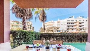 Una tavola imbandita per due con vista su una piscina e edifici sullo sfondo.