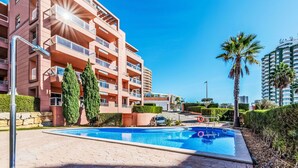 Un moderno edificio residenziale con piscina, palme e cielo azzurro.