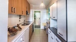 Una cucina moderna con mobili in legno, lavandino in acciaio inossidabile, forno a microonde integrato e un frigorifero grande.