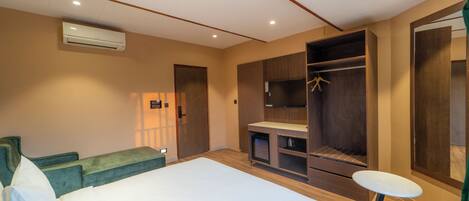 Habitación de hotel con cama, sofá verde, mesita, armario y televisor.