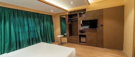Una habitación de hotel con cama, televisión, armario y una mesita.