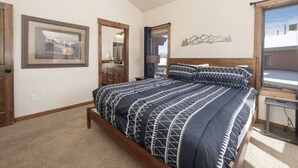 A bedroom with a bed, a dresser, a mirror, and a window with a view of the outside. - Hot Tub | Mountain Views | Steps to Trails (Winter Park)