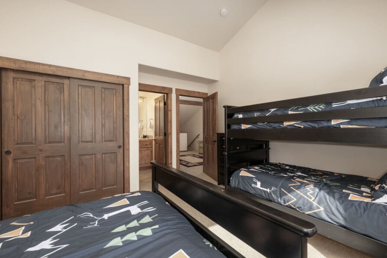 A bedroom with two beds, wooden wardrobe, and a door leading to another room.