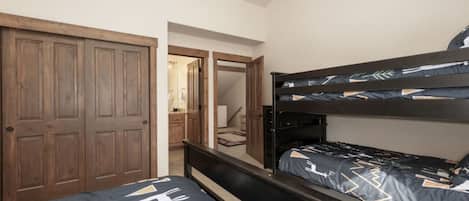 A bedroom with two beds, wooden wardrobe, and a door leading to another room.