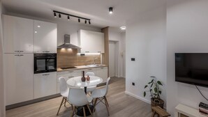 Una cocina moderna con armarios blancos, una isla central y un comedor con sillas blancas.