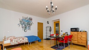 Una habitación con una cama, una mesa de comedor con sillas, un microondas y un armario.