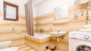 Une salle de bain équipée d’une baignoire, de toilettes, d’un lavabo et d’un lave-linge.
