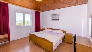 Une chambre à coucher avec un lit en bois, une table de chevet, un bureau et une fenêtre avec des rideaux.