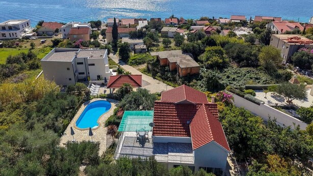 Zona residencial costera con casas, piscina y vista al mar.