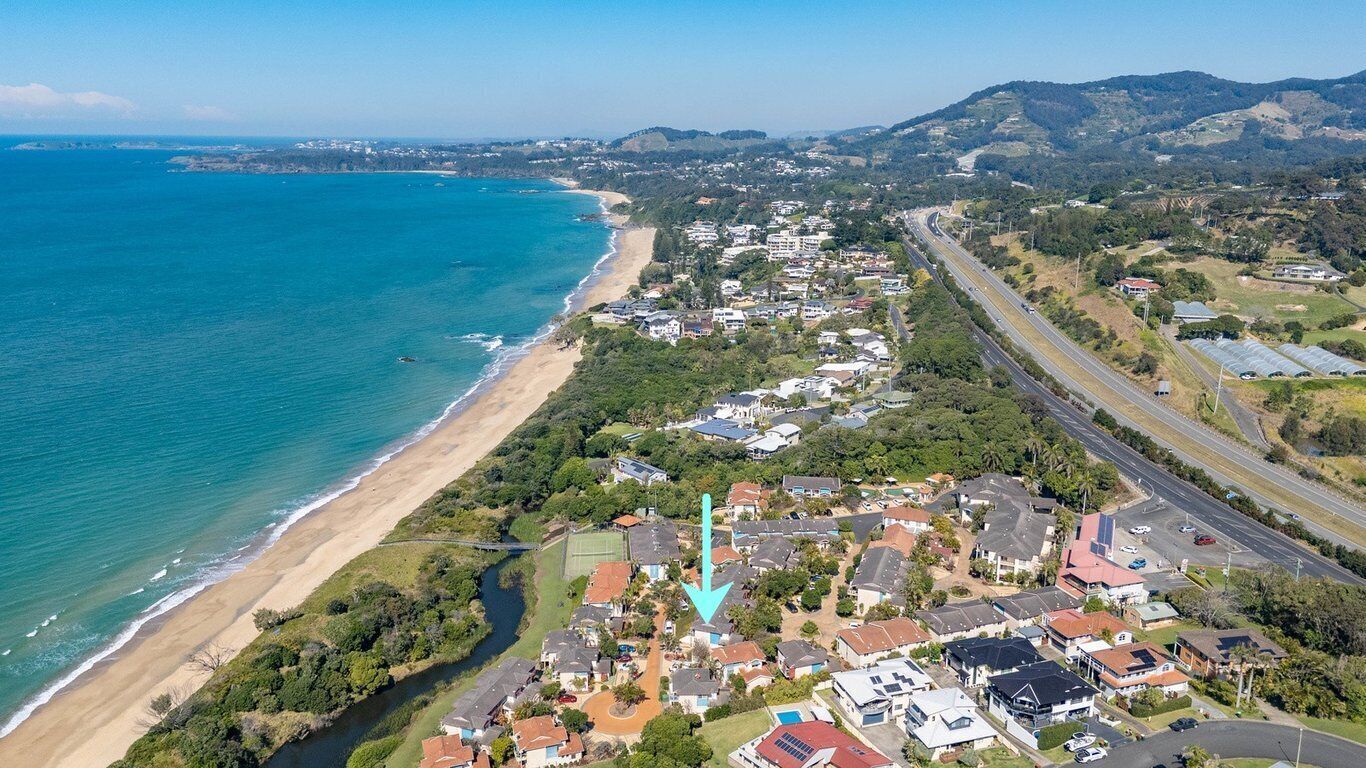 Vista aérea de una zona residencial costera con casas, una playa y una autopista.