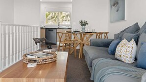 A modern living room with a grey sofa, a coffee table, and a dining area with a wooden table and chairs.