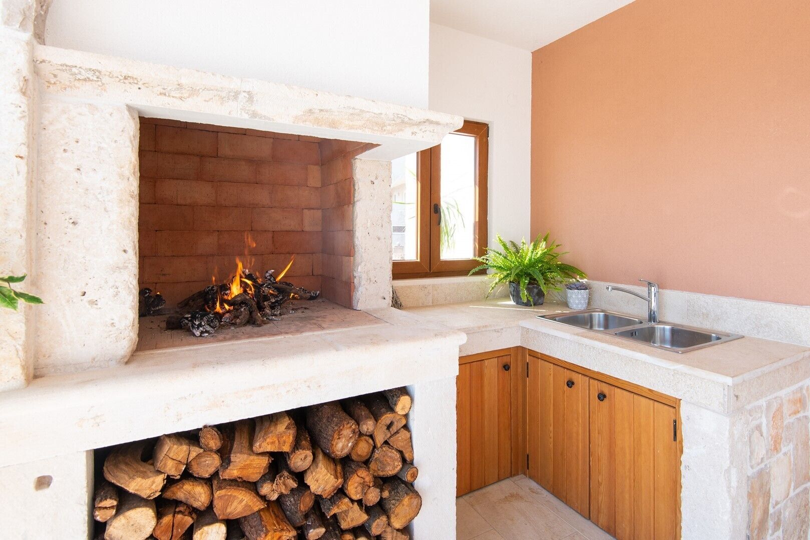 A kitchen with a stone fireplace, a sink, and wooden cabinets.