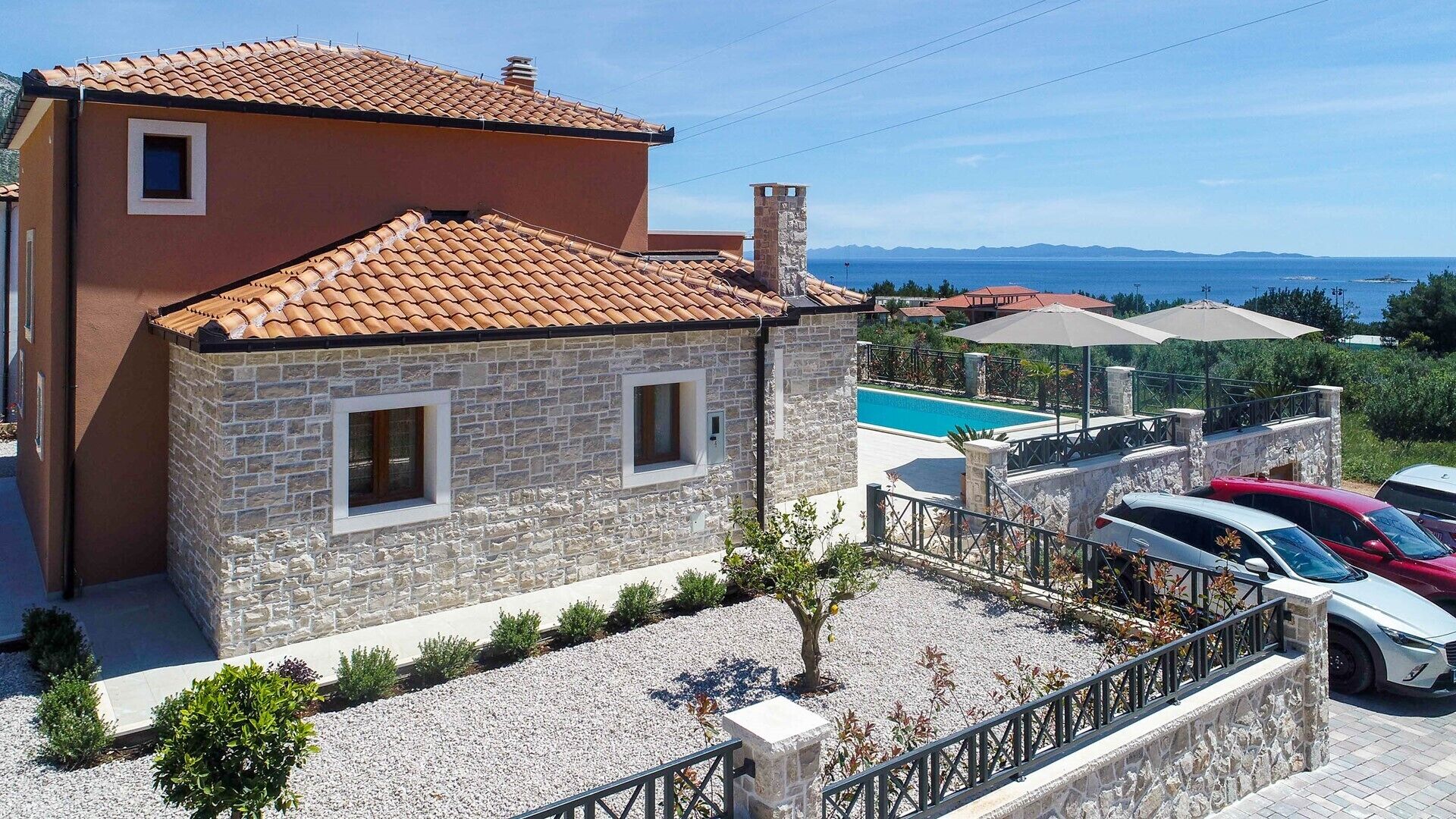 Ein zweistöckiges Steinhaus mit Ziegeldach, Swimmingpool und Meerblick.