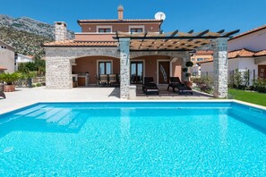 Relax by the pool surrounded by lounge chairs and a mountain backdrop.