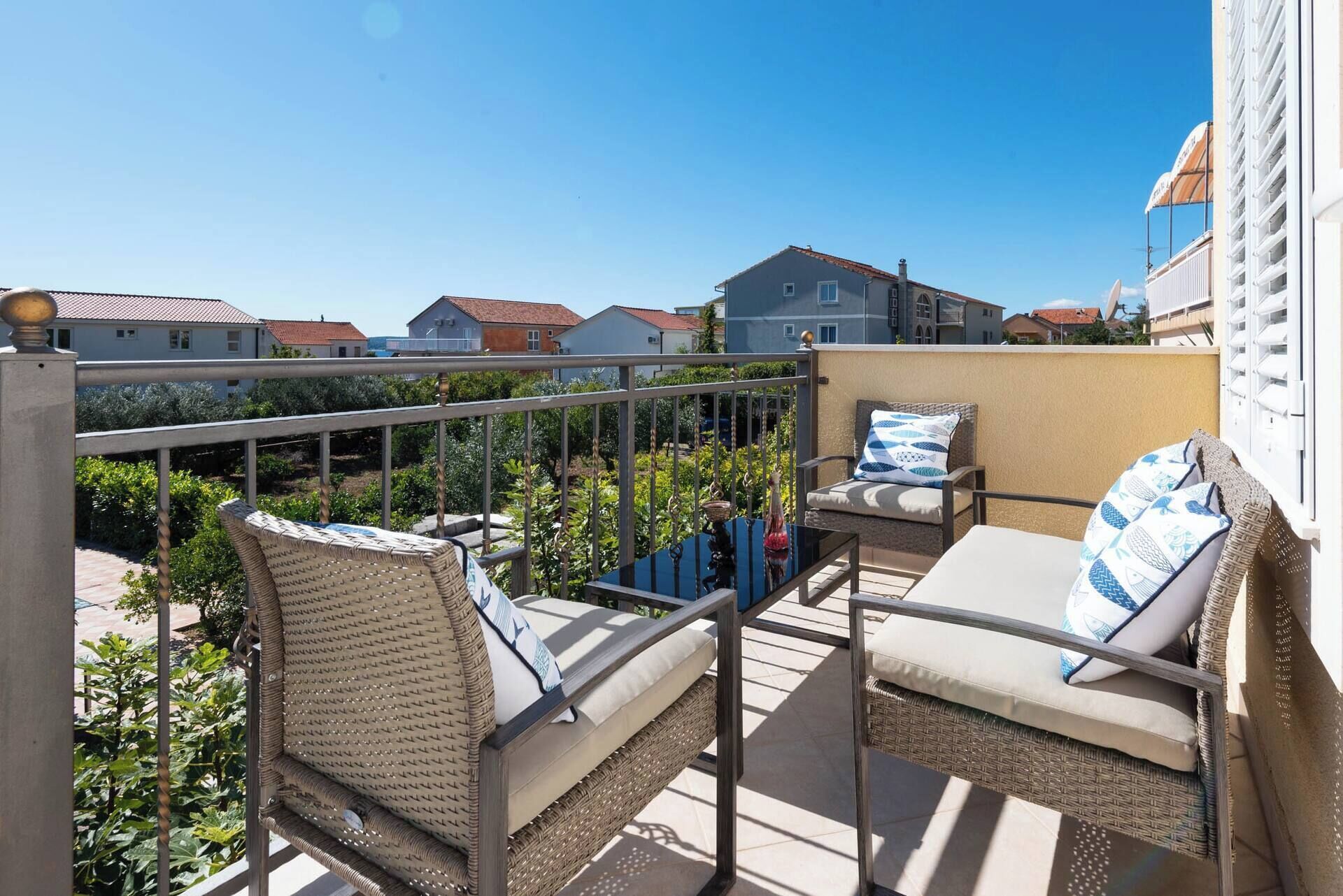 Un balcón con muebles de mimbre y vistas a casas vecinas.