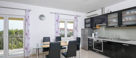 Una cocina moderna con armarios negros, un refrigerador de acero inoxidable y un horno empotrado.