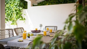 Un área de comedor al aire libre con sillas de mimbre y una mesa preparada para el desayuno.
