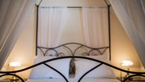 Una cama con estructura metálica, ropa de cama blanca y dosel.