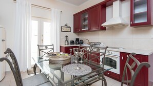 Una cocina moderna con armarios rojos, una estufa blanca y un comedor con mesa y sillas de vidrio.