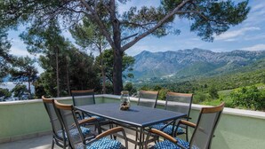 A terrace with a table and chairs, overlooking a mountainous landscape. - 2-Bedroom Apartment Mokalo with amazing sea view! (Orebic)