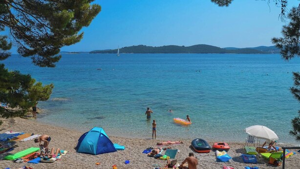 A beach with clear blue water, a tent, and people relaxing. - Beautiful Holiday Villa Natura with swimming pool and magnificent sea view! (Orebic)