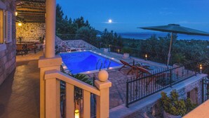 A pool area with a stone deck, lounge chairs, and a view of the sea. - Beautiful Holiday Villa Natura with swimming pool and magnificent sea view! (Orebic)