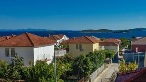 A coastal residential area with terracotta-roofed houses, a clear blue sky, and a view of the sea and distant islands. - Great 2-Bedroom Apartment for up to 6 persons (Orebic)