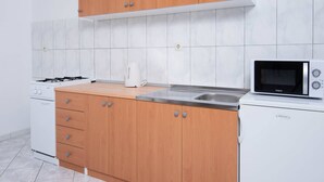 A modern kitchen with wooden cabinets, a gas stove, a microwave, and a sink. - Great 2-Bedroom Apartment for up to 6 persons (Orebic)