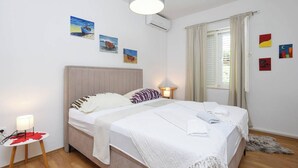 A bedroom with a bed, bedside lamps, a small table with a lamp, and artwork on the walls.
