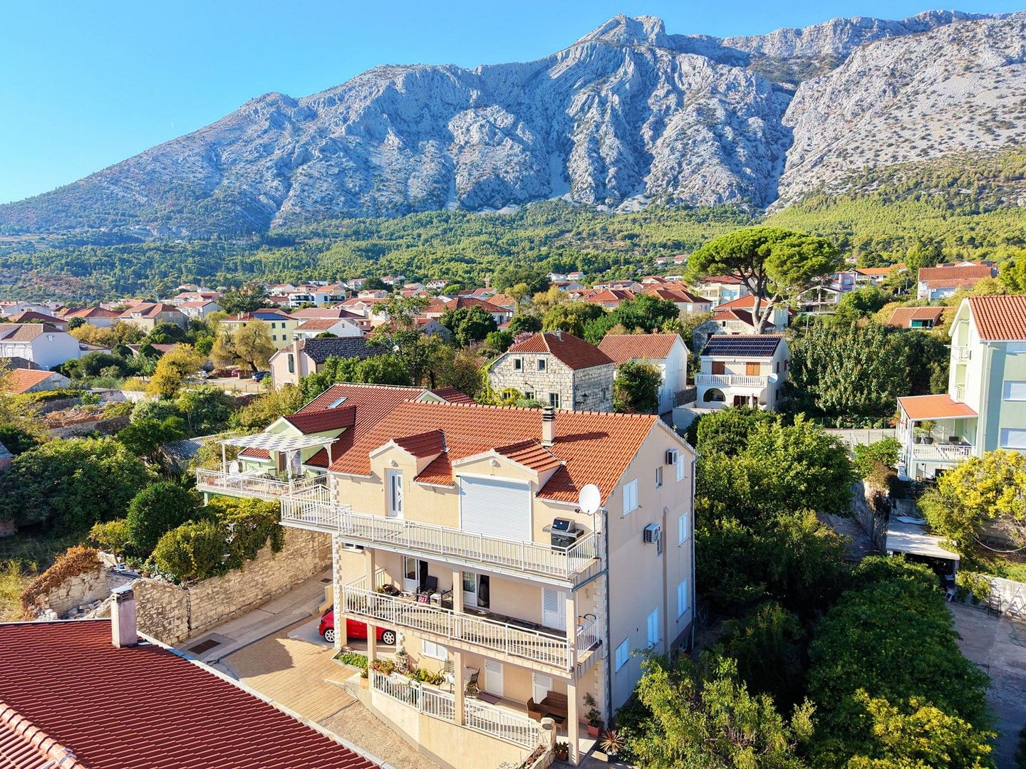 A residential area with houses, some with balconies, and a mountainous backdrop.