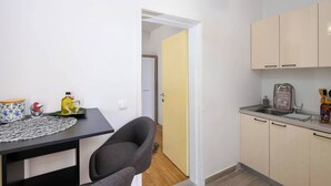 A compact kitchen with a sink, cabinets, and a dining area with a table and chair. - Beautiful 1-Bedroom Apartment Sandra (Orebic)