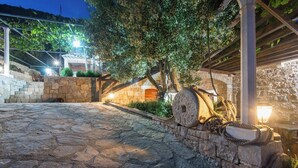 A stone-paved outdoor area with a pergola and stone walls, illuminated by ambient lighting. - The Hidden Treasure Village, 7-Bedroom Luxury Holiday Resort with children playground, private Pool and Private Parking, SEA VIEW (Orebic)