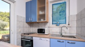 A kitchen with a microwave, oven, sink, and blue cabinets. - Charming Studio Apartment with Sea View (Orebic)