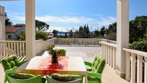 A covered outdoor area with a table and chairs, a view of the sea, and a white railing. - Charming Studio Apartment with Sea View (Orebic)