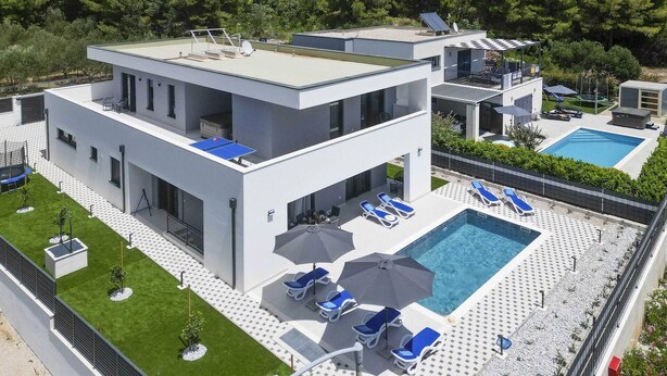Un bâtiment moderne à deux étages, doté d’une terrasse sur le toit, d’une piscine et d’une pelouse bien entretenue.