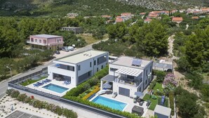 Un hôtel moderne doté de deux piscines, entouré d’une végétation luxuriante et avec des montagnes en toile de fond.