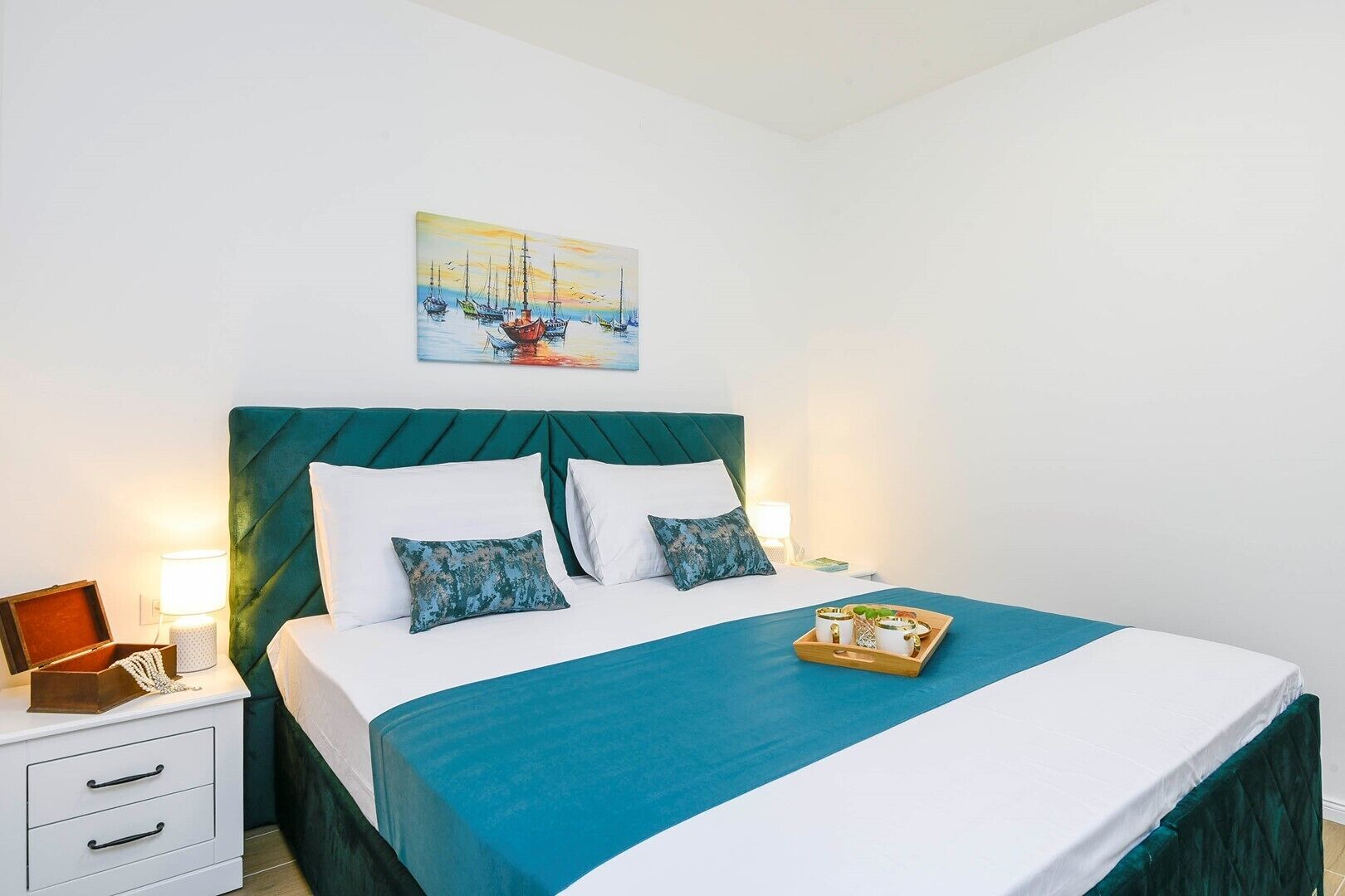 Habitación de hotel ordenada con cama, mesita de noche y un cuadro en la pared.