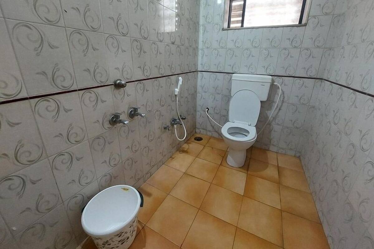 Een badkamer met betegelde vloer, toilet, douchetoilet en prullenbak.